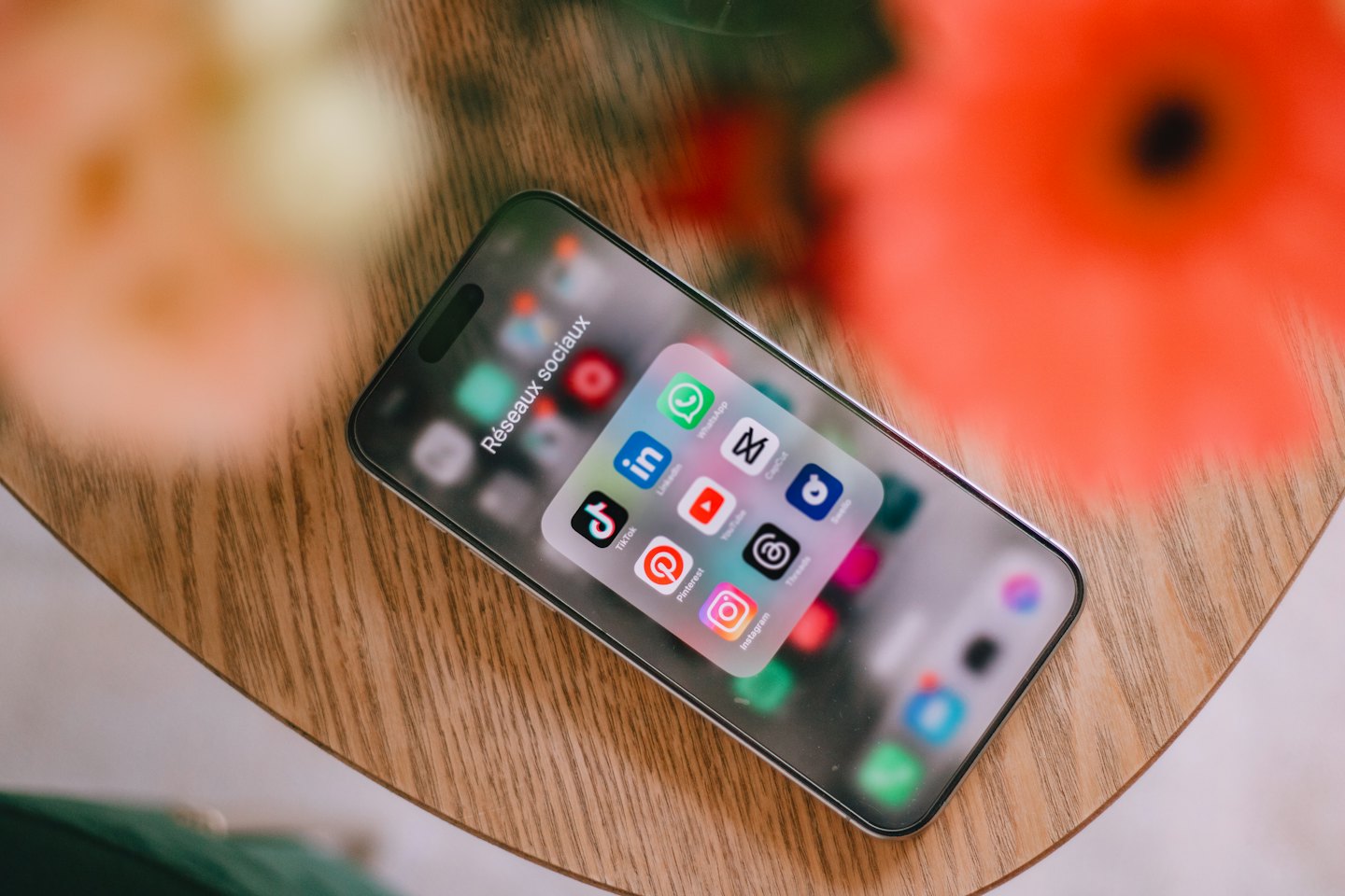 Smartphone-Bildschirm mit Social-Media-Symbolen auf einem Holztisch.
