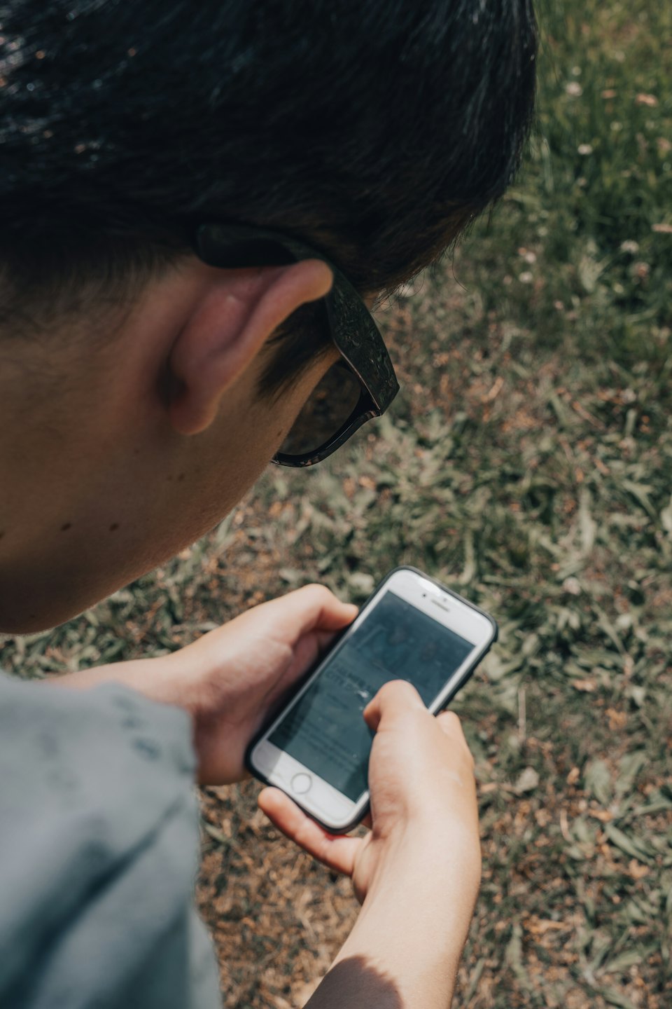 Hände tippen auf einem weißen Smartphone-Bildschirm im Freien.